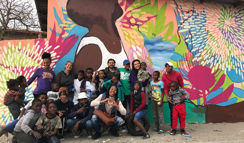 SF State early childhood education students and community members pose in front of the new community mural they painted this summer.
